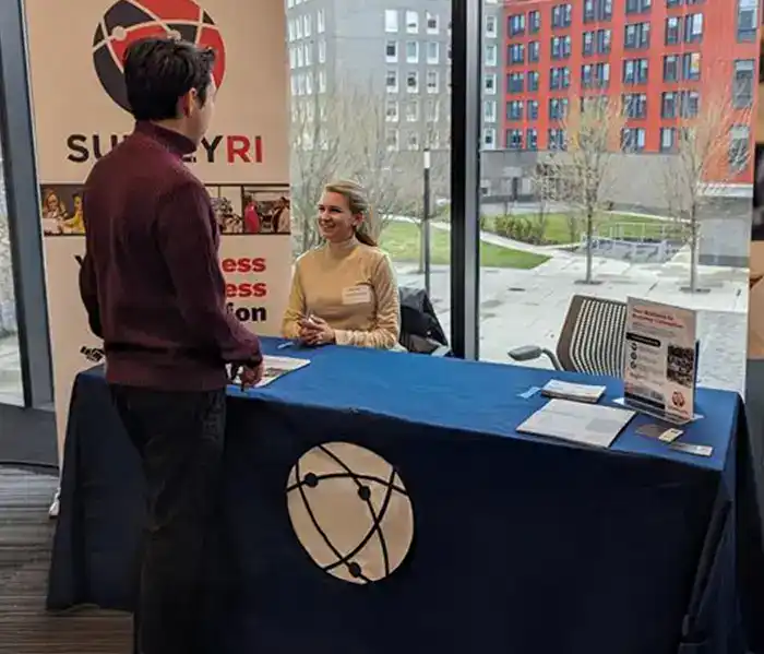 two people speaking at the SupplyRI table at an event